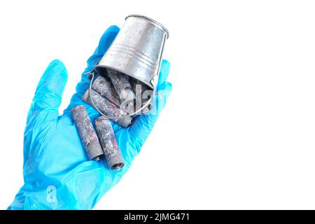 Miniatureimer aus stark korrodierten AA-Batterien in einer Handschuhen, isoliert auf weißem Hintergrund. Stockfoto