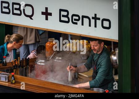 London, Großbritannien - 09 2022. Juni: Mann kocht in einem Street-Food-Pavillon am Borough Market, London Stockfoto