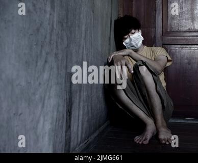 Asiatischer junger Mann mit Gesichtsmaske. Konzept von Burnout, Müdigkeit, Schwäche oder Erschöpfung. Stockfoto