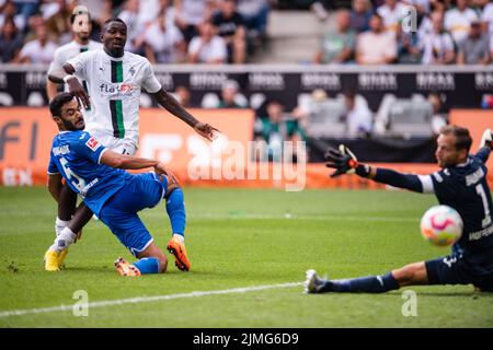 06. August 2022, Nordrhein-Westfalen, Mönchengladbach: Fußball: Bundesliga, Borussia Mönchengladbach - TSG 1899 Hoffenheim, Matchday 1, Borussia-Park. Gladbachs Marcus Thuram (Mitte) punktet gegen Hoffenheims Ozan Kabak (l) und Torhüter Oliver Baumann mit 2:1. Foto: Marius Becker/dpa - WICHTIGER HINWEIS: Gemäß den Anforderungen der DFL Deutsche Fußball Liga und des DFB Deutscher Fußball-Bund ist es untersagt, im Stadion und/oder des Spiels aufgenommene Fotos in Form von Sequenzbildern und/oder videoähnlichen Fotoserien zu verwenden oder zu verwenden. Stockfoto