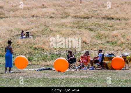 London, Großbritannien. 6. August 2022. Im gelb verbrannten Gras auf dem Parliament Hill spazieren die Menschen und picknicken – das heiße Wetter setzt die Dürreverhältnisse auf Hampstead Heath fort. Kredit: Guy Bell/Alamy Live Nachrichten Stockfoto