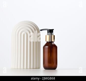 Braune Glasflasche mit schwarzer Pumpe von Kosmetikprodukten auf weißem Tisch. Natürliche Bio-Spa-Kosmetik, Beauty-Konzept Stockfoto