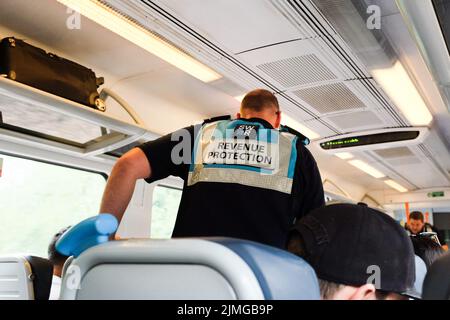 Ein Fahrkartenkontrollbeamter der South Western Railway, der durch einen Eisenbahnwaggon fährt. Stockfoto