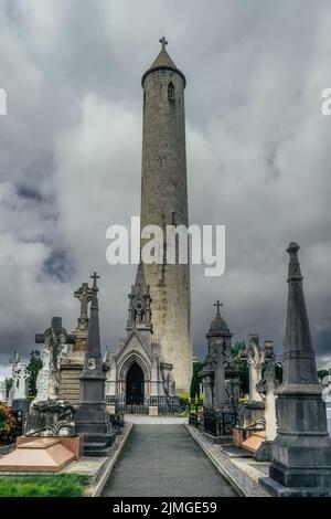 Alte Gräber und Grabsteine auf dem Friedhof von Glasnevin mit dem Round Tower, Irland Stockfoto