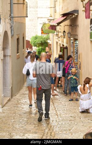 Touristen in einer Gasse mit Geschäften in der Altstadt von Krk in Kroatien Stockfoto