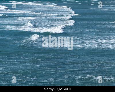 Schöner weißer Schaum auf türkisfarbenen Flutwellen. Die Oberfläche des Wassers als Hintergrund. Blaues Meerwasser Stockfoto