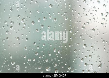 Regentropfen auf einer Fensterscheibe bei regnerischem Wetter Stockfoto