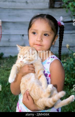 Ein junges Mädchen aus der amerikanischen Ureinwohner hält ein Kätzchen im Indianerreservat Fort Hall, Fort Hall Idaho Stockfoto