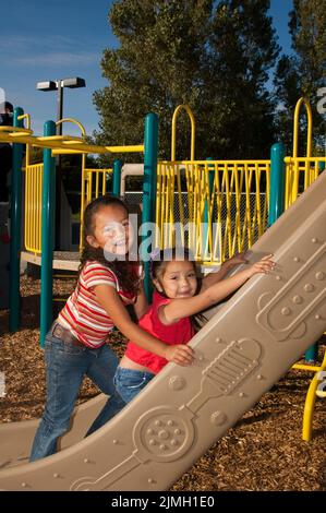 Zwei indianische Kinder spielen auf einer Folie verbunden, andere Spielgeräte Stockfoto