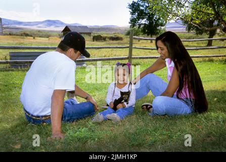 Die dreiköpfige indianische Familie spielt mit dem Haustier Kätzchen. Eltern lehren das junge Mädchen, wie es sich um ihr Haustier kümmert. Fort Hall Idaho Stockfoto