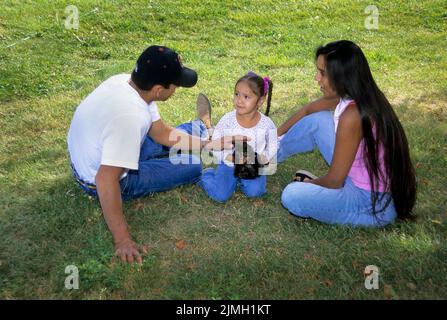 Die dreiköpfige indianische Familie spielt mit dem Haustier Kätzchen. Eltern lehren das junge Mädchen, wie es sich um ihr Haustier kümmert. Fort Hall Idaho Stockfoto