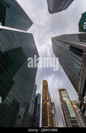 Glasfassaden von Wolkenkratzern des Finanzviertels von Singapur an einem bewölkten Abend, Ansicht von unten, Weitwinkelobjektiv, Stadtzentrum, BU Stockfoto