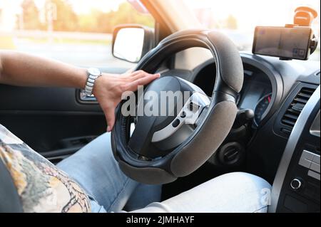 Konzept einer gefährlichen Reise. Eine Hand eines Mannes hält das Lenkrad, während er ein Auto fährt. Männer Fahren. Konzeptuelle Fotografie des Autofahrens. Stockfoto