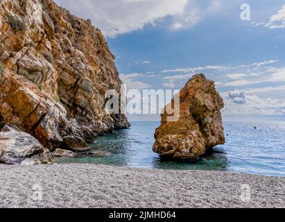 Abgeschiedener felsiger Strand mit klarem, türkisfarbenem Wasser und braunen Sandsteinklippen Stockfoto