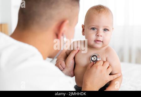 Rückansicht Arzt hört kleines Baby mit Stethoskop Stockfoto