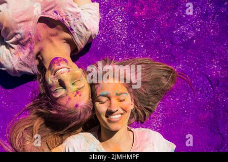 Junge Frauen mit holi Puder liegen lila Farbe bedeckt Stockfoto