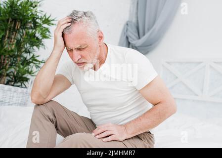 Älterer Mann mit Kopfschmerzen Stockfoto