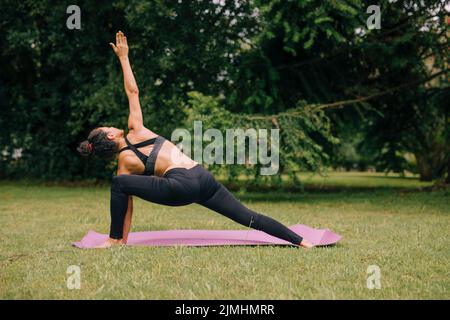 Junge Yogi Attraktive Frau, die Yoga-Garten praktiziert Stockfoto