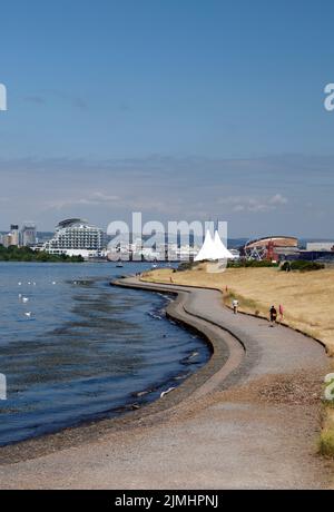 Wanderer genießen den gewundenen Pfad entlang der Cardiff Bay Barrage .August 2022. Sommer Stockfoto