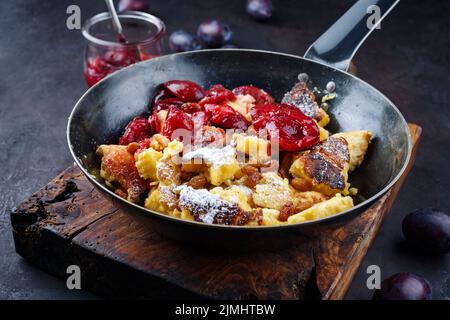 Der traditionelle österreichische Kaiserschmarren mit Pflaumen und Rosinen diente als Nahaufnahme in einer rustikalen Bratpfanne Stockfoto