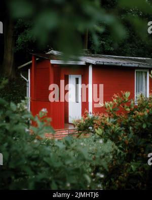 Eine vertikale Aufnahme einer typischen schwedischen Hütte in der Farbe „Falun-Kupfer-Rot“ in einem Garten Stockfoto