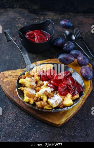 Der traditionelle österreichische Kaiserschmarren mit Pflaumen und Rosinen diente als Nahaufnahme in einer rustikalen Bratpfanne Stockfoto