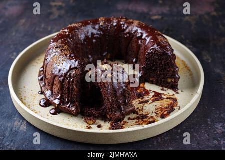 Traditioneller Schokoladenkuchen mit Glasurglasur und braunem Muscovado-Zucker, der als Nahaufnahme auf einem Teller serviert wurde Stockfoto