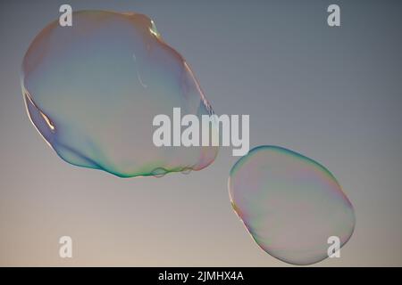 Große Blase, die über dem blauen Himmel fliegt. Riesige bunte Seifenblasen fliegen über bewölktem Himmel Hintergrund. Stockfoto