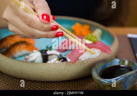 Frau, die leckeres Sushi isst, Nahaufnahme von Essstäbchen. Stockfoto