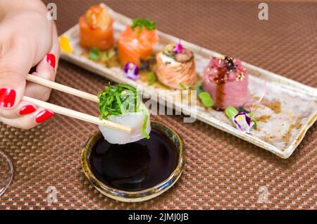 Frau, die leckeres Sushi isst, Nahaufnahme von Essstäbchen. Stockfoto