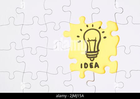 Gelbe Idee Puzzle heben sich von weißen Stücken Stockfoto