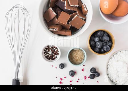 Zutaten für Kuchen mit Schneebesen auf weißem Hintergrund Stockfoto