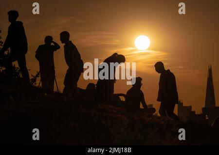 London, Großbritannien. 6.. August 2022. Wetter in Großbritannien: Dramatische Silhouetten bei Sonnenuntergang von der Spitze des Greenwich Parks, da die Hitzetemperaturen der Stadt voraussichtlich Mitte 30s in der nächsten Woche eintreffen werden, nachdem Südengland den trockensten Juli seit Beginn der Rekorde im Jahr 1836 erlebt hat, wobei London nur acht Prozent seiner durchschnittlichen Niederschläge verzeichnete. Kredit: Guy Corbishley/Alamy Live Nachrichten Stockfoto