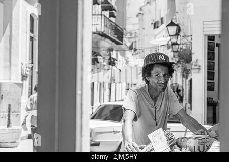 Ein Kubaner in den späten 20er Jahren, der Obst und Gemüse von seinem Wagen verkaufte. Fotografiert durch das Fenster eines Restaurants. Havanna, Kuba. Stockfoto