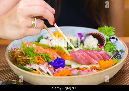 Frau, die köstliche Sashimi isst, Nahaufnahme von Essstäbchen. Stockfoto