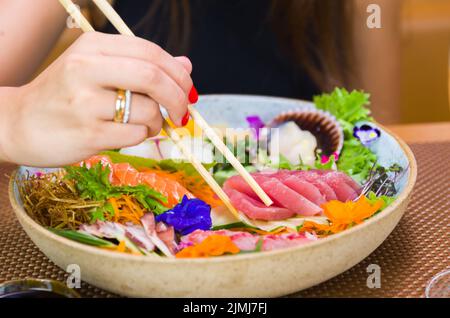 Frau, die köstliche Sashimi isst, Nahaufnahme von Essstäbchen. Stockfoto