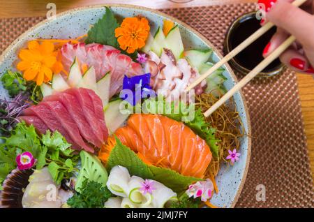 Frau, die köstliche Sashimi isst, Nahaufnahme von Essstäbchen. Stockfoto