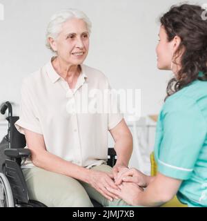 Glückliche behinderte Krankenschwester sitzen Rollstuhl suchen Hausmeister Stockfoto