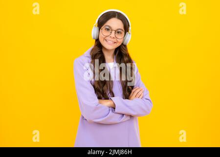 Kindermusik-Konzept. Teenager Kind Mädchen tanzt im Rhythmus der Melodie, hört Lied in Kopfhörern. Kind hört Musik über Kopfhörer. Stockfoto