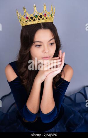 Teenager Prinzessin Kind feiert Erfolg Sieg und Sieg. Teen Mädchen in Königin Krone auf grauem Hintergrund isoliert. Stockfoto