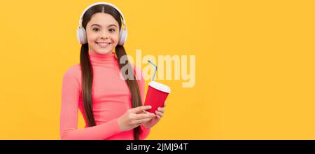 Lassen Sie uns versuchen. Fröhliches Kind mit Kaffee zum Mitnehmen Tasse mit Kopfhörern. Guten Morgen. Horizontales Poster mit isoliertem Kindergesicht, Banner-Header, Kopierbereich. Stockfoto