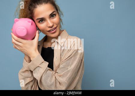Portrait Foto von glücklich positive niedlich junge schöne hübsche Brünette lockige Frau mit aufrichtigen Emotionen tragen stilvolle beige sh Stockfoto