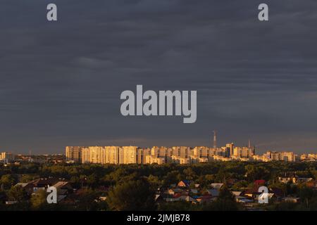 Panoramablick auf die Stadt mit Skyline mit blauem Himmel mit hohen Gebäuden und einem Sektor von Hütten mit Bäumen. Stockfoto