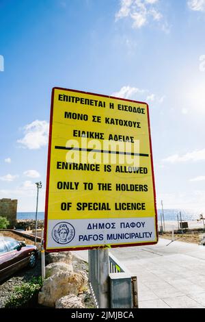 Paphos, Zypern - 29. Okt 2014: Straßenansicht des gelben Schildes mit Text in griechischer und englischer Sprache der Eintritt ist nur für Inhaber einer speziellen Lizenz erlaubt Stockfoto