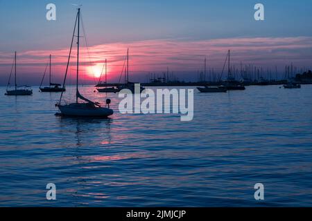 Sonnenaufgang an der Küste. In der Silhouette der Schiffe im Hafen. Selektiver Fokus Stockfoto