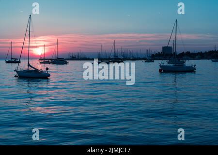 Sonnenaufgang an der Küste. In der Silhouette der Schiffe im Hafen. Selektiver Fokus Stockfoto