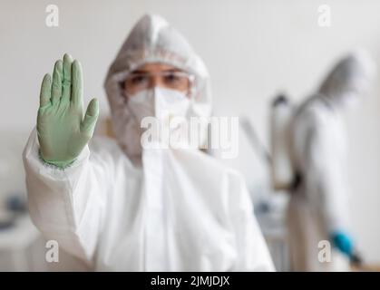 Personen, die Schutzausrüstung tragen und gefährliche Bereiche desinfizieren Stockfoto