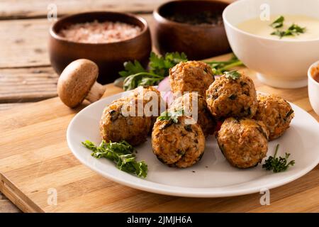 Nahaufnahme von frischen Fleischbällchen mit essbaren Pilzen und Tauchschüssel auf Schneidebrett Stockfoto