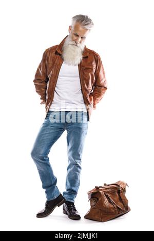 Hübscher bärtiger älterer Mann mit Ledertasche und Jacke auf weißem Hintergrund Stockfoto