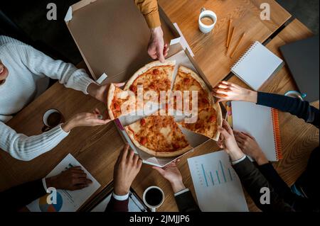 Kollegen aus der Draufsicht, die während der Büromeeting-Pause Pizza essen Stockfoto